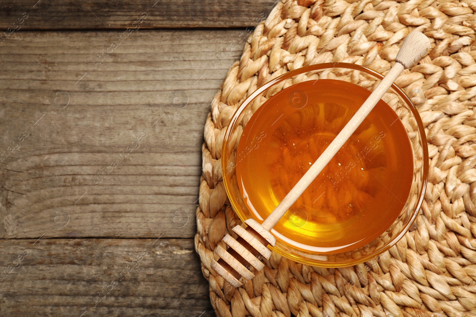 Photo of Delicious honey in bowl and dipper on wooden table, top view. Space for text