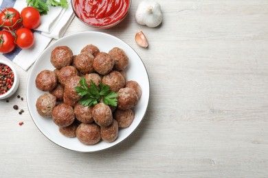 Photo of Tasty cooked meatballs with parsley on white wooden table, flat lay. Space for text