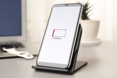 Photo of Mobile phone charging with wireless device on light grey stone table