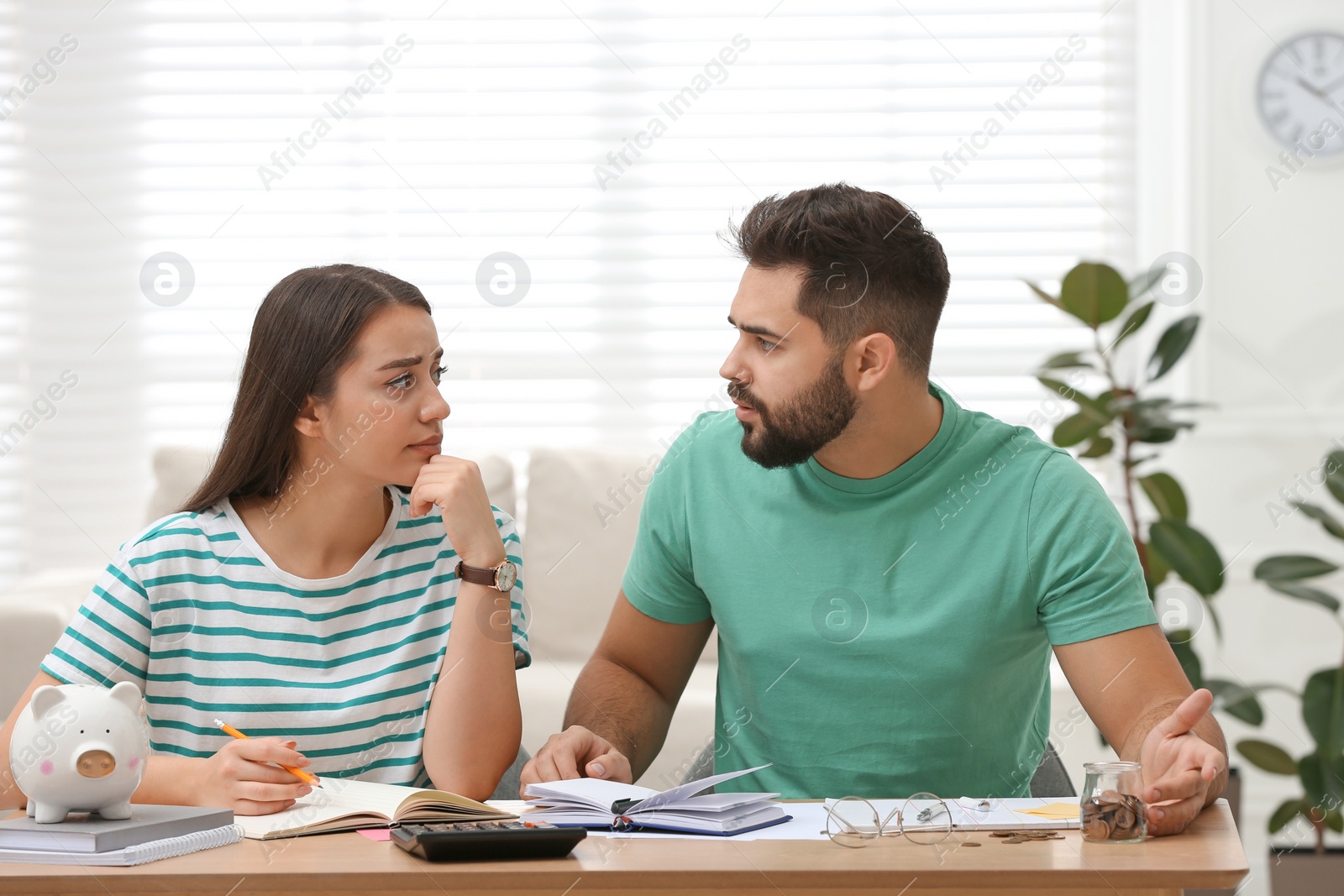 Photo of Worried young couple planning family budget at wooden table indoors