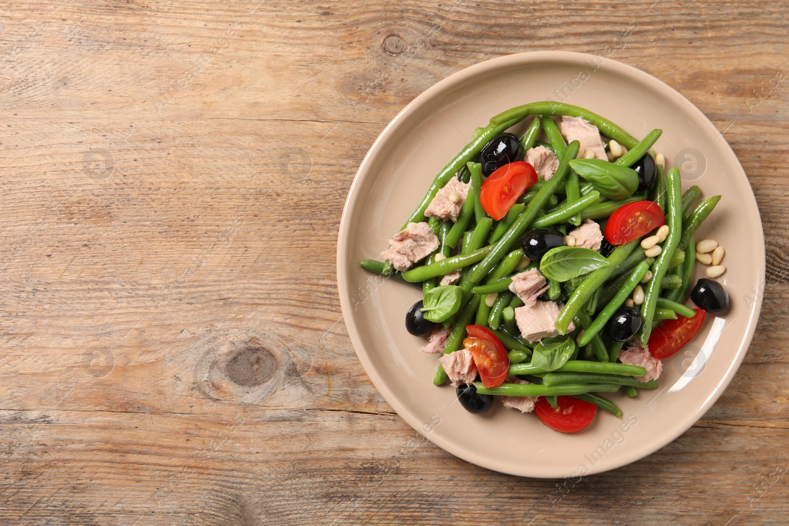 Photo of Plate of tasty salad with green beans on wooden table, top view. Space for text