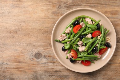 Photo of Plate of tasty salad with green beans on wooden table, top view. Space for text