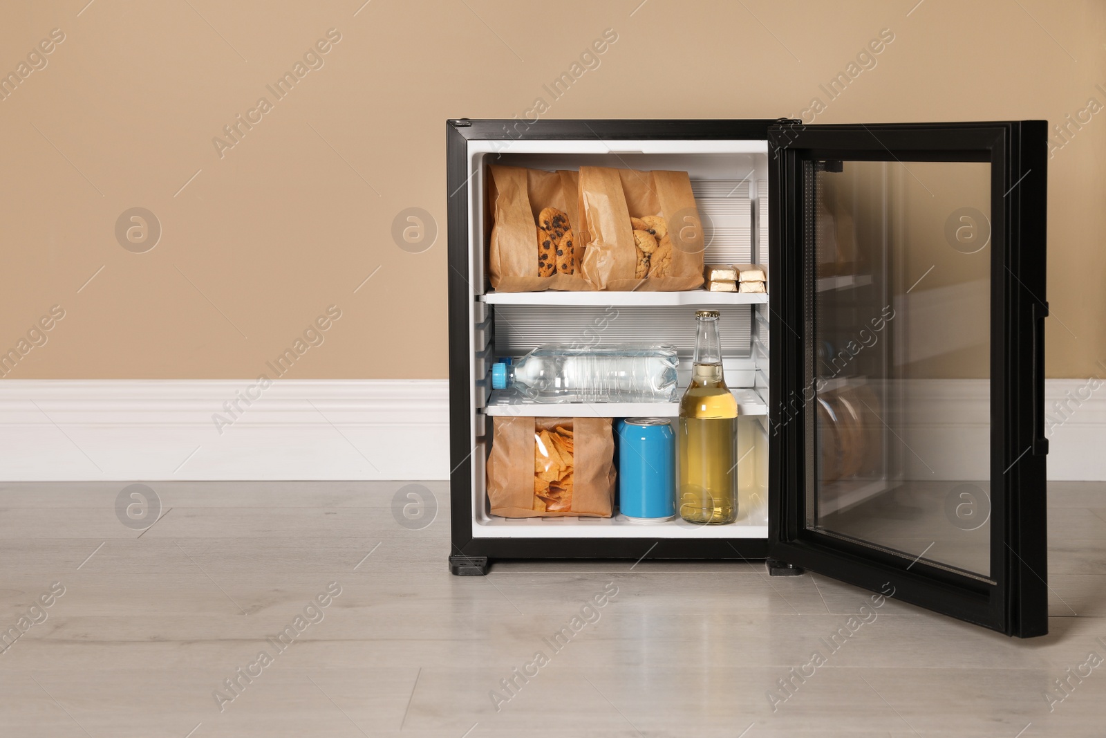 Photo of Mini bar filled with food and drinks near beige wall indoors, space for text