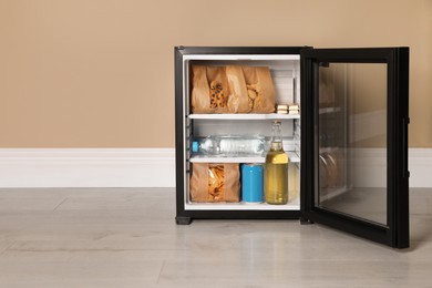 Photo of Mini bar filled with food and drinks near beige wall indoors, space for text