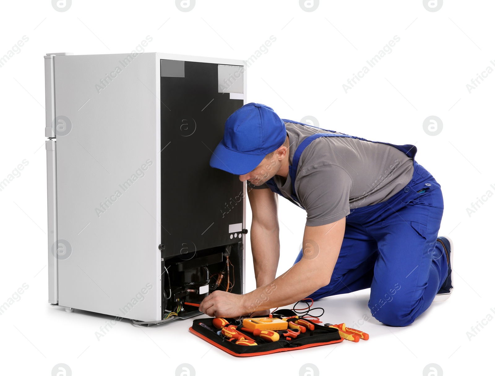 Photo of Male technician in uniform repairing refrigerator on white background