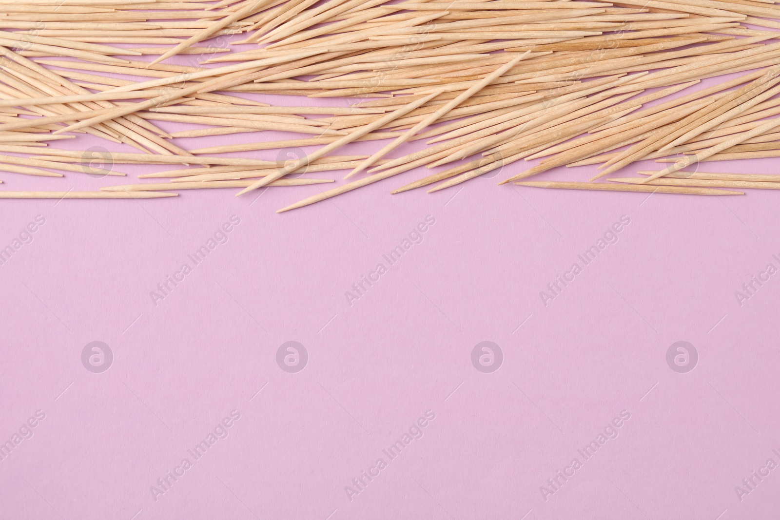 Photo of Wooden toothpicks on pink background, flat lay. Space for text