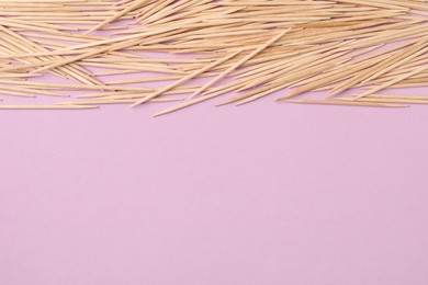 Wooden toothpicks on pink background, flat lay. Space for text