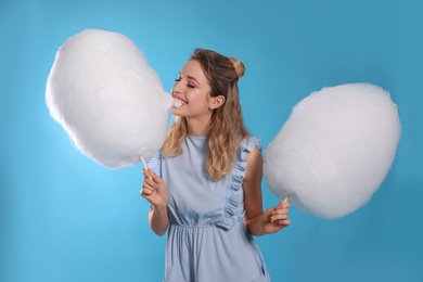 Photo of Portrait of pretty young woman with cotton candy on blue background