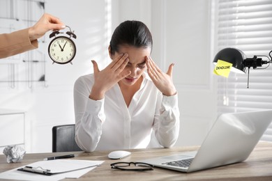 Deadline concept. Boss holding alarm clock near stressed worker at desk in office