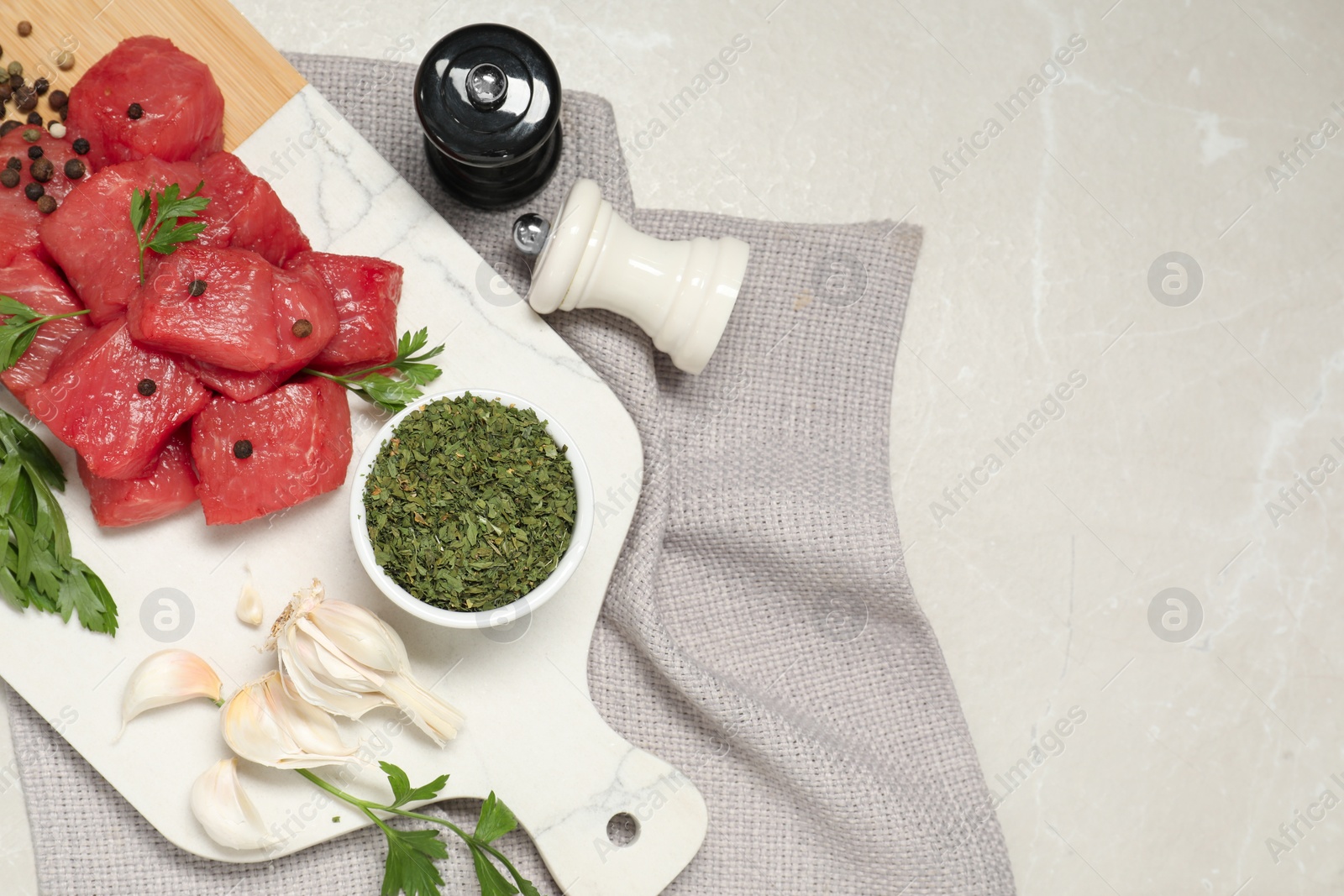 Photo of Raw beef meat and different ingredients for cooking delicious goulash on light grey marble table, flat lay. Space for text