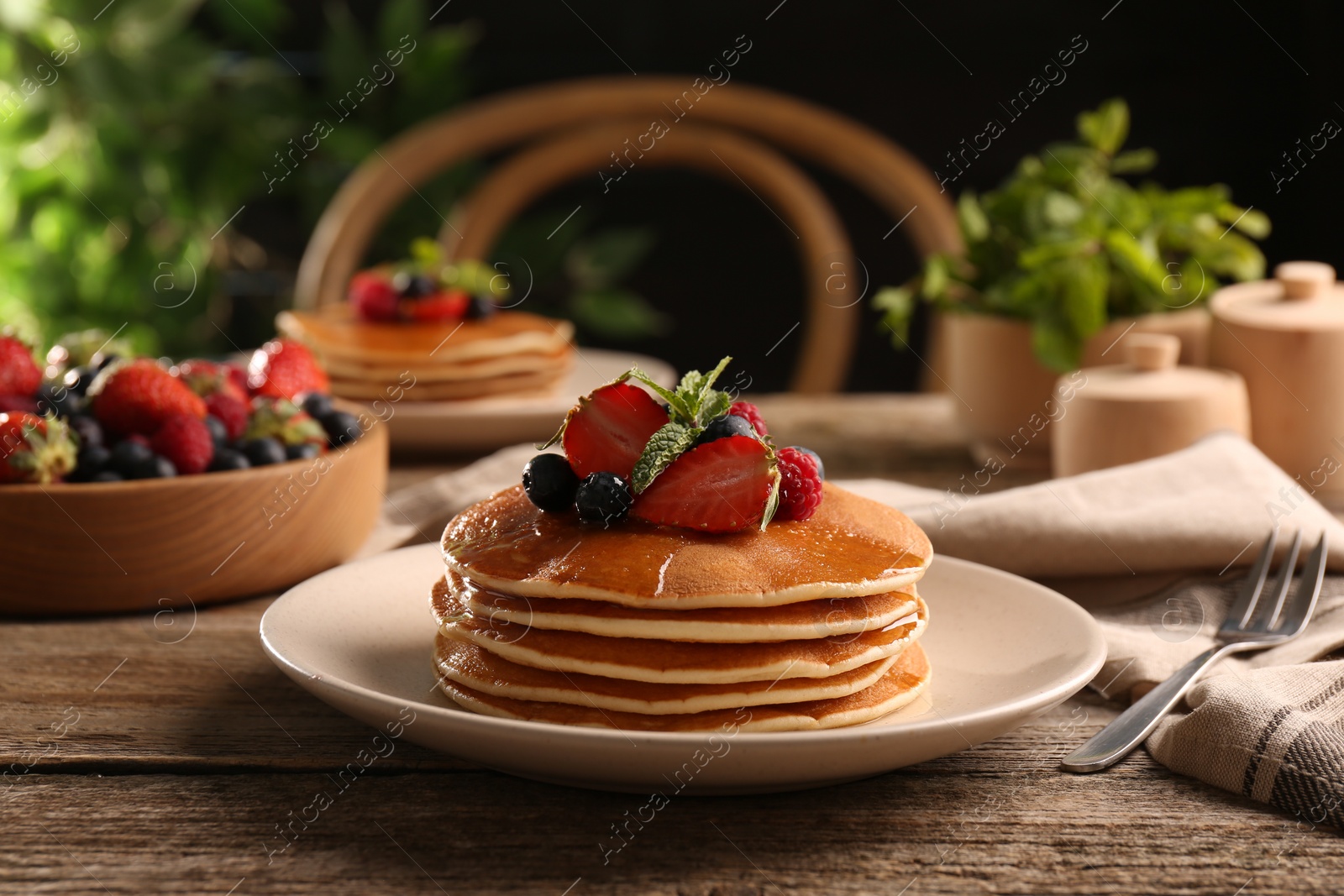 Photo of Tasty pancakes with fresh berries and mint on wooden table