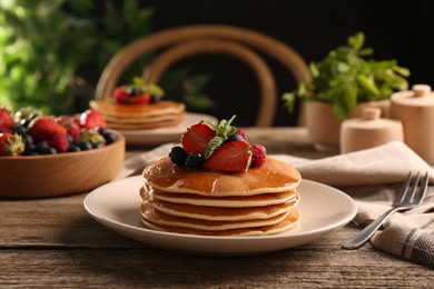 Tasty pancakes with fresh berries and mint on wooden table