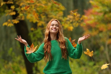 Photo of Autumn vibes. Happy woman throwing leaves up in park