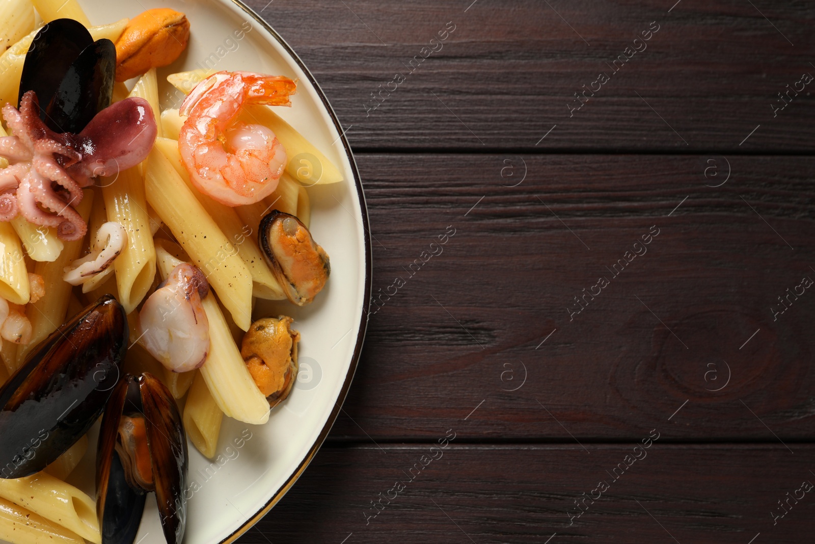 Photo of Delicious pasta with seafood served on wooden table, top view. Space for text