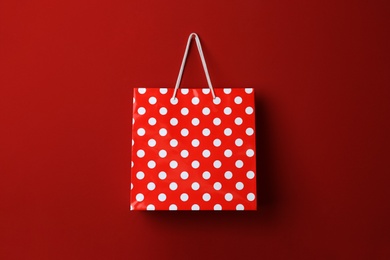 Photo of Paper shopping bag hanging on red background