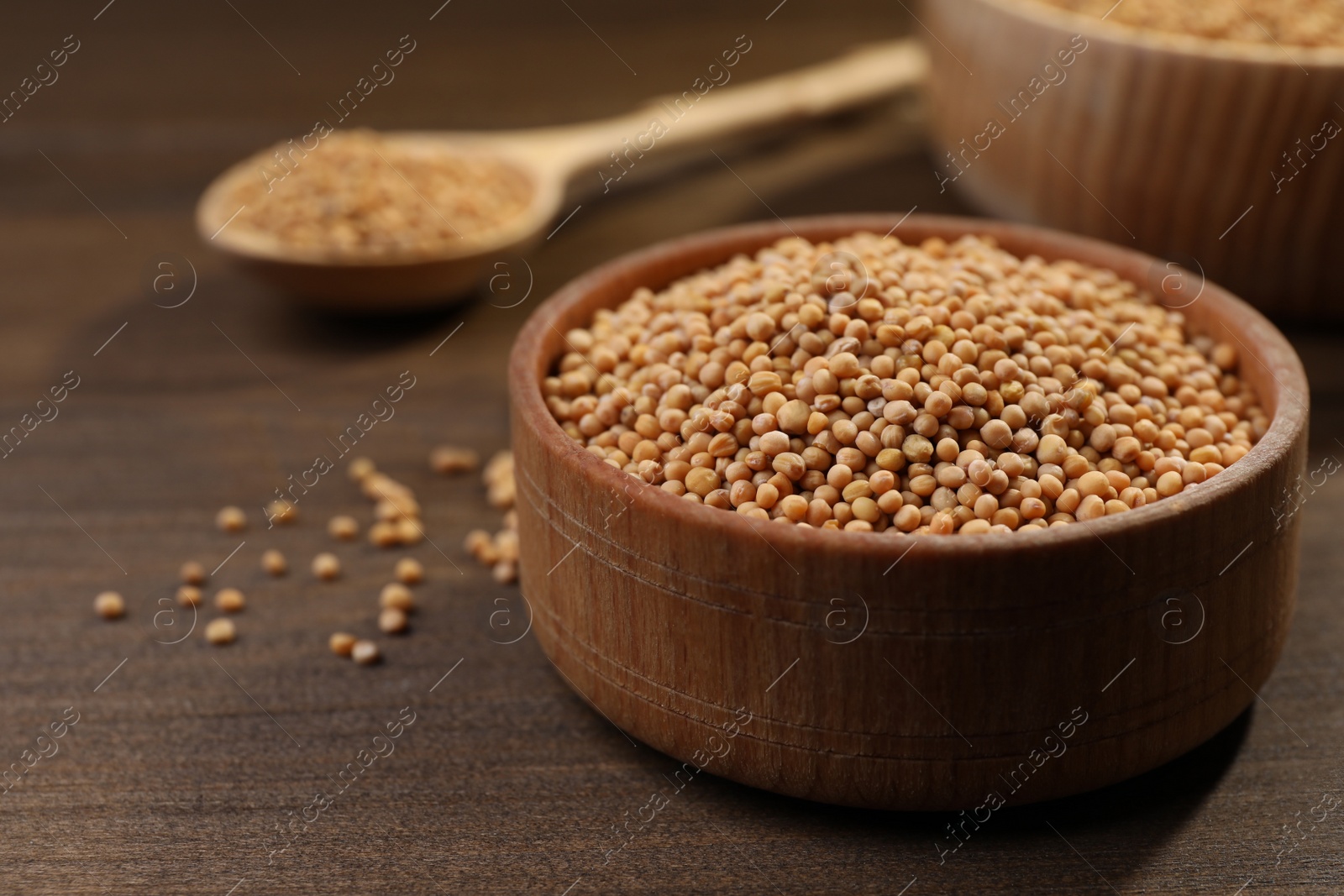 Photo of Mustard seeds in wooden bowl on table, closeup. Space for text