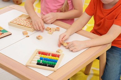 Photo of Children playing with different math game kits at desk indoors, closeup. Study mathematics with pleasure