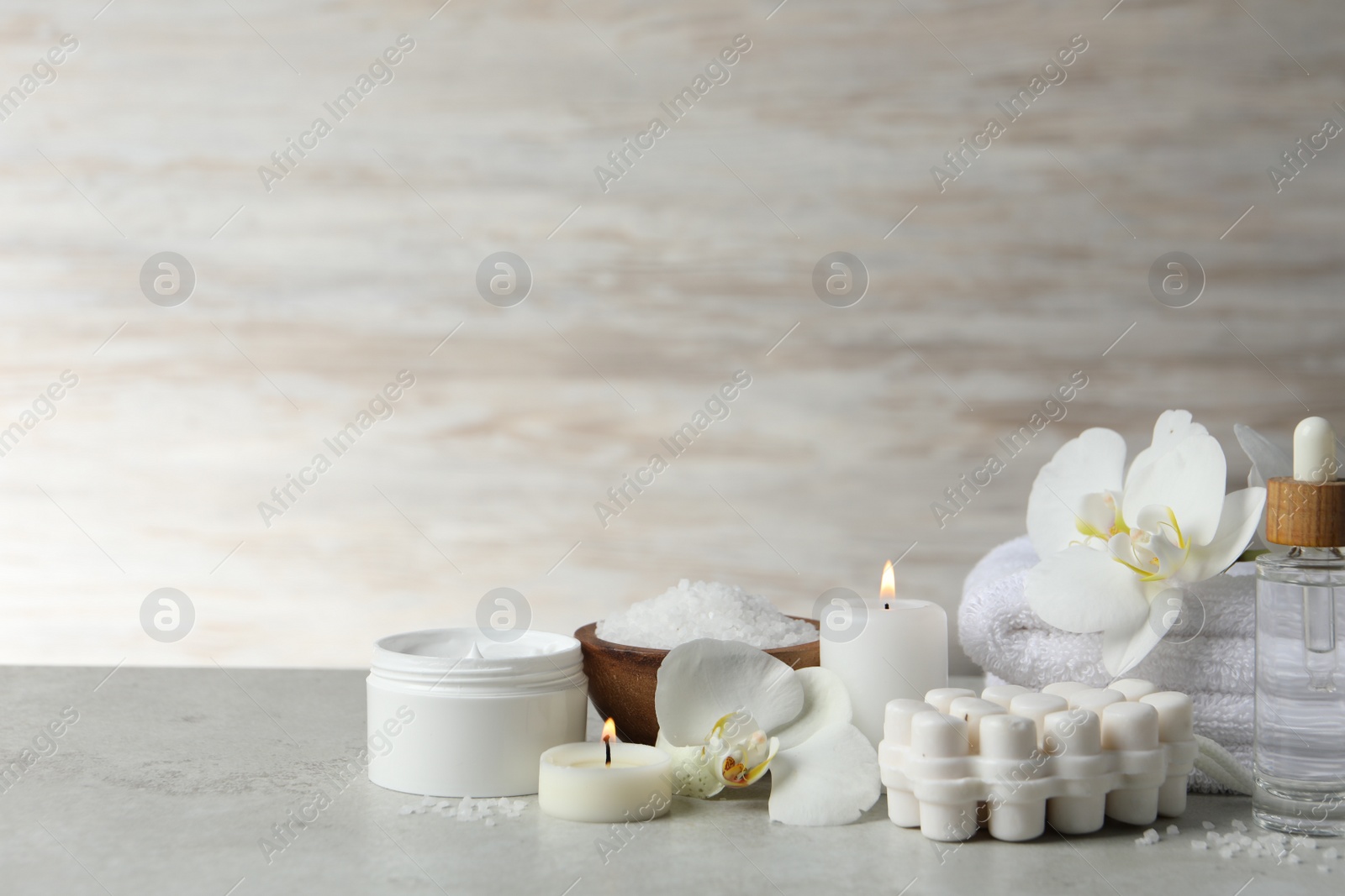 Photo of Beautiful composition with different spa products, burning candles and flowers on light grey table. Space for text