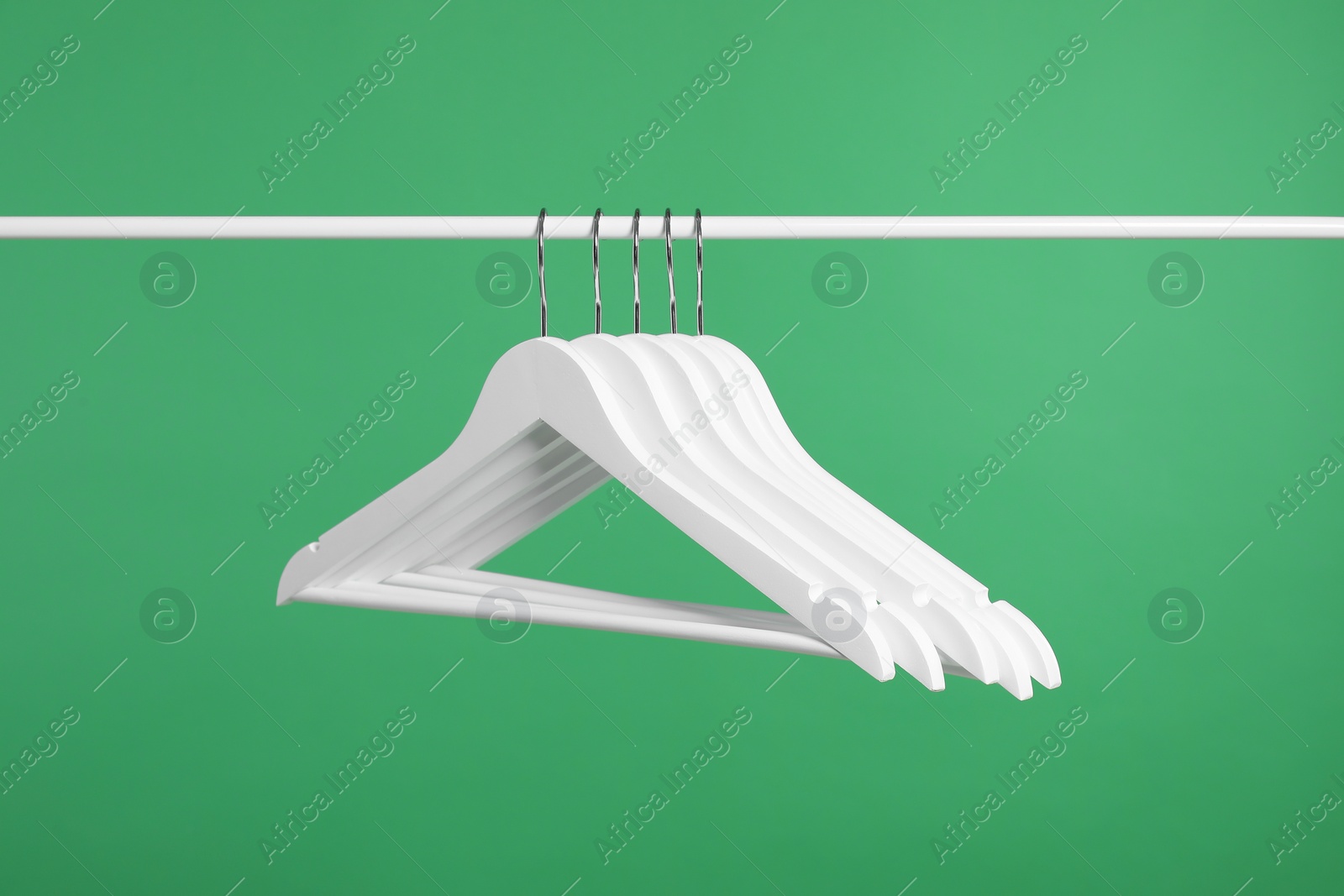 Photo of Empty clothes hangers on rack against green background