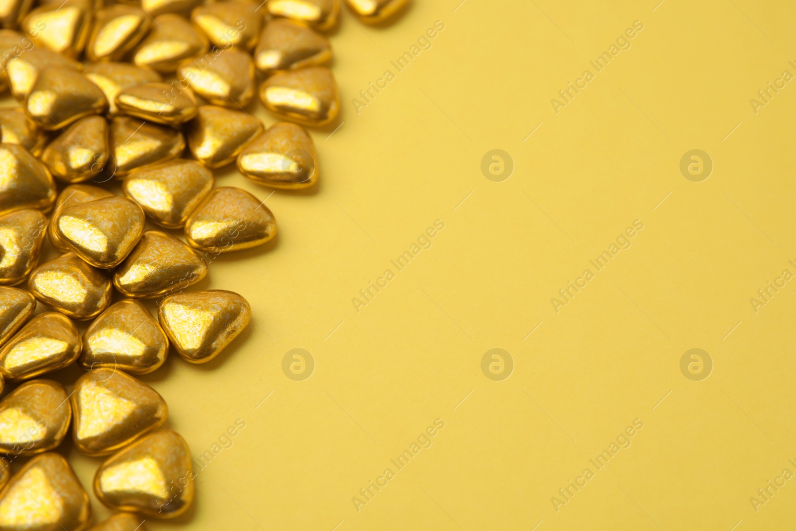 Photo of Many delicious heart shaped candies on yellow background. Space for text