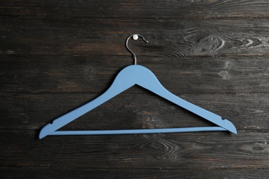 Photo of Empty clothes hanger on wooden wall. Wardrobe accessory