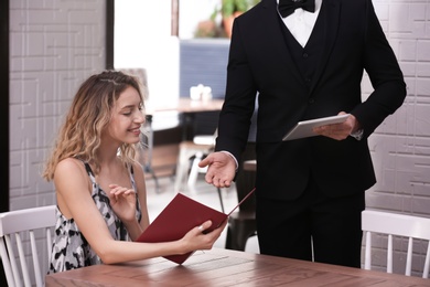 Photo of Young waiter taking order from client in restaurant