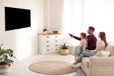 Photo of Happy family watching TV on sofa at home