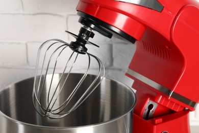 Photo of Modern red stand mixer near white brick wall, closeup