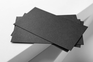 Blank black business cards on light background, closeup. Mockup for design