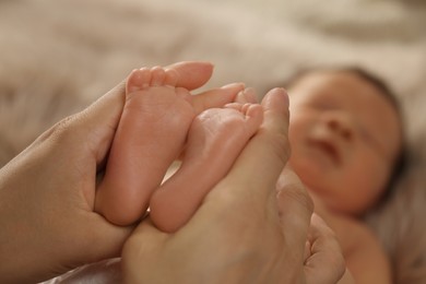 Photo of Mother holding her newborn baby, closeup view on feet. Lovely family