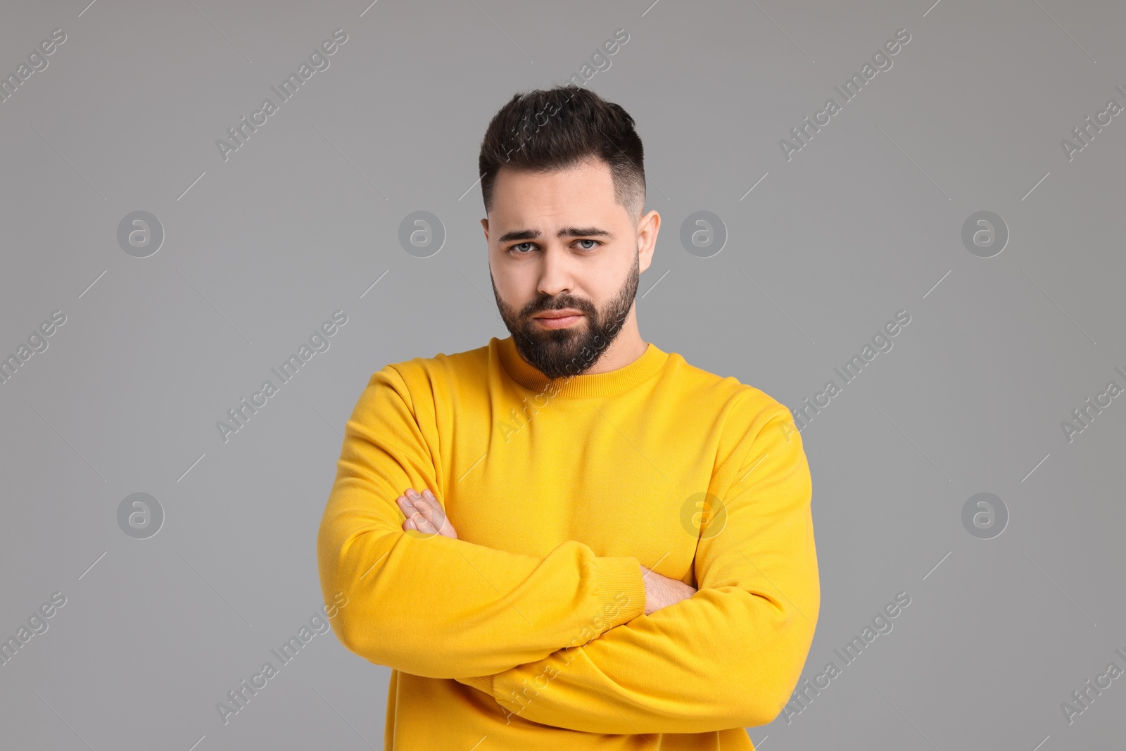 Photo of Portrait of sad man with crossed arms on light grey background