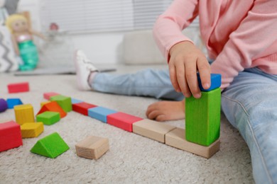 Cute little girl playing with colorful building blocks at home, closeup