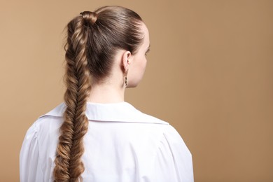 Photo of Woman with braided hair on brown background, back view. Space for text