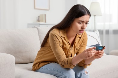 Photo of Confused woman with credit card at home. Be careful - fraud