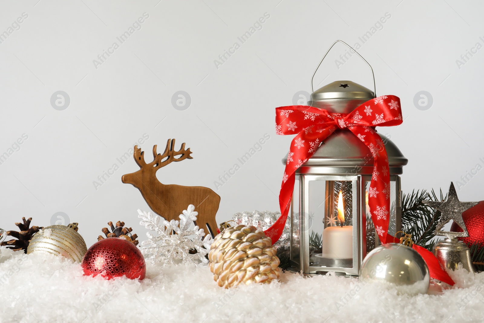 Photo of Beautiful composition with vintage Christmas lantern and festive decorations on snow against white background