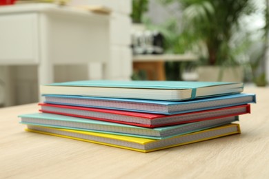Photo of Stack of colorful planners on wooden table indoors