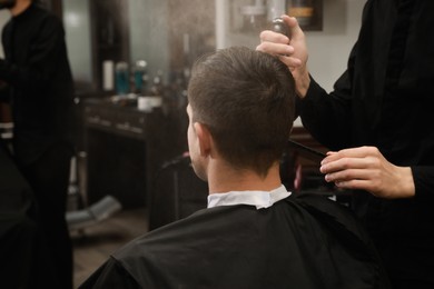 Photo of Professional hairdresser making stylish haircut in salon, back view