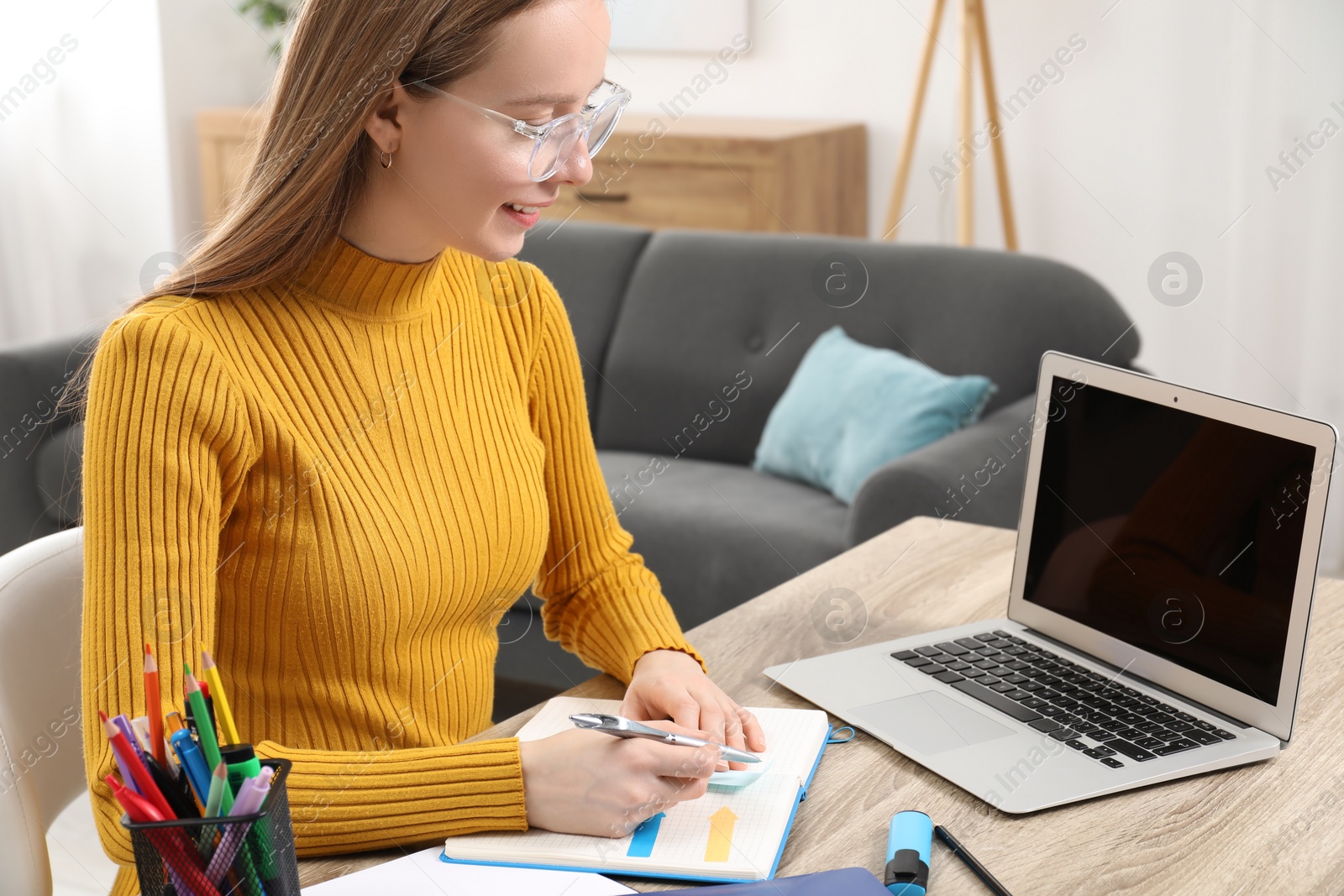 Photo of Woman taking notes at wooden table in office