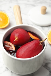 Poaching pears in mulled wine on white marble table, closeup