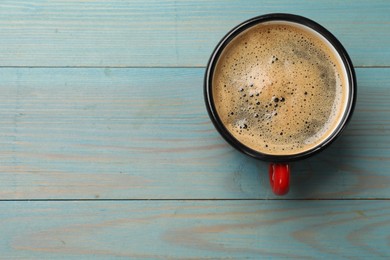 Cup of aromatic coffee on light blue wooden table, top view. Space for text