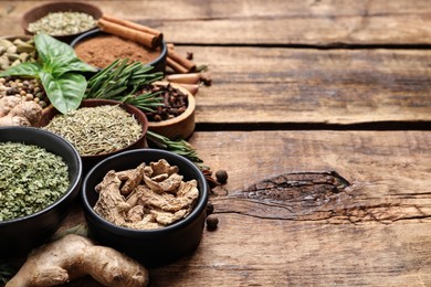 Different natural spices and herbs on wooden table, space for text