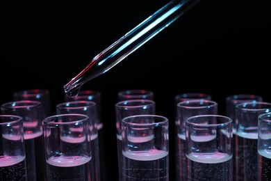 Photo of Dripping reagent into test tube on black background, closeup. Laboratory analysis