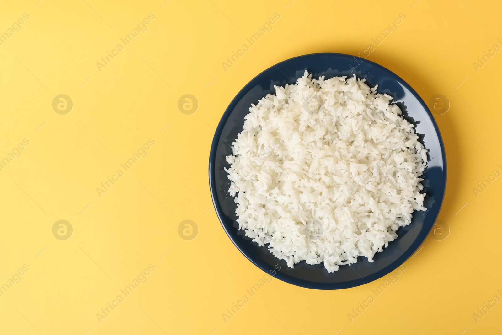 Photo of Plate of boiled rice on color background, top view with space for text