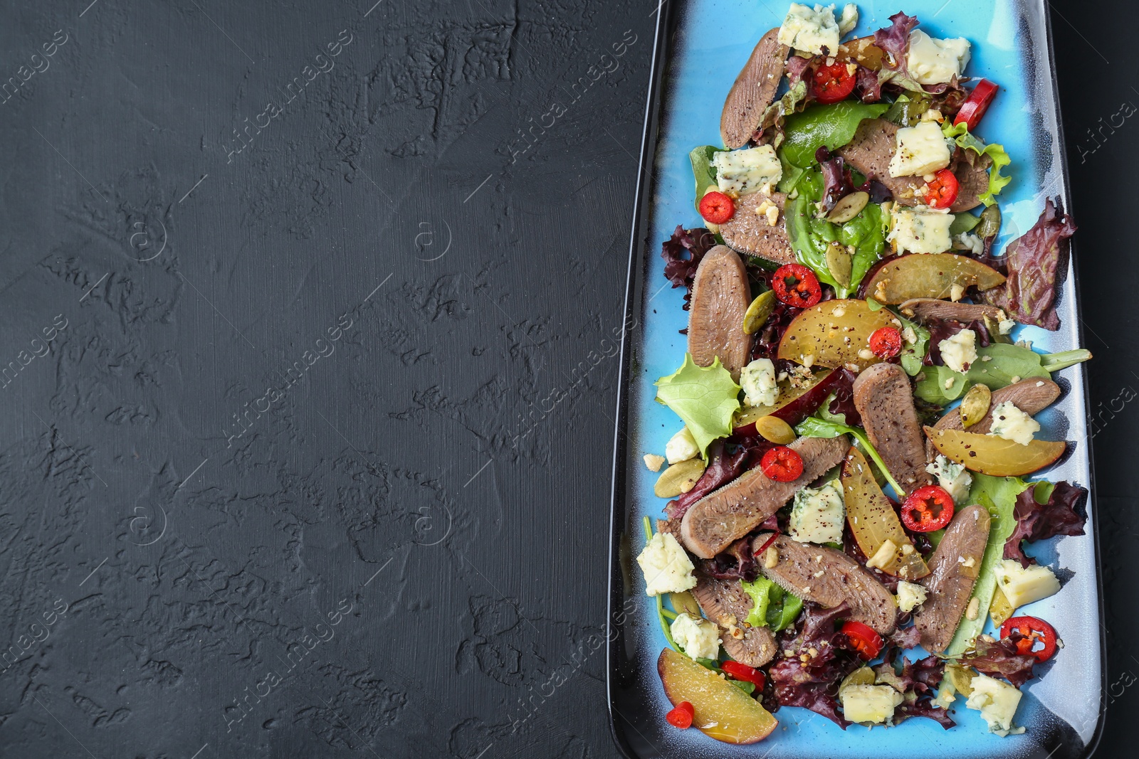 Photo of Delicious salad with beef tongue and cheese on black textured table, top view. Space for text