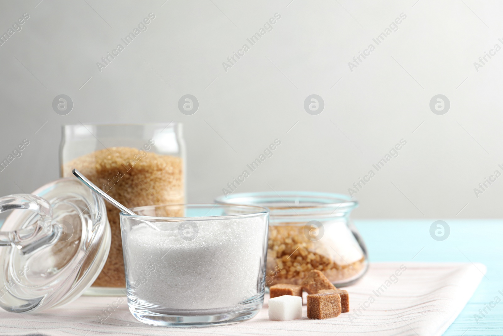 Photo of Various bowls with sugar on light blue wooden table