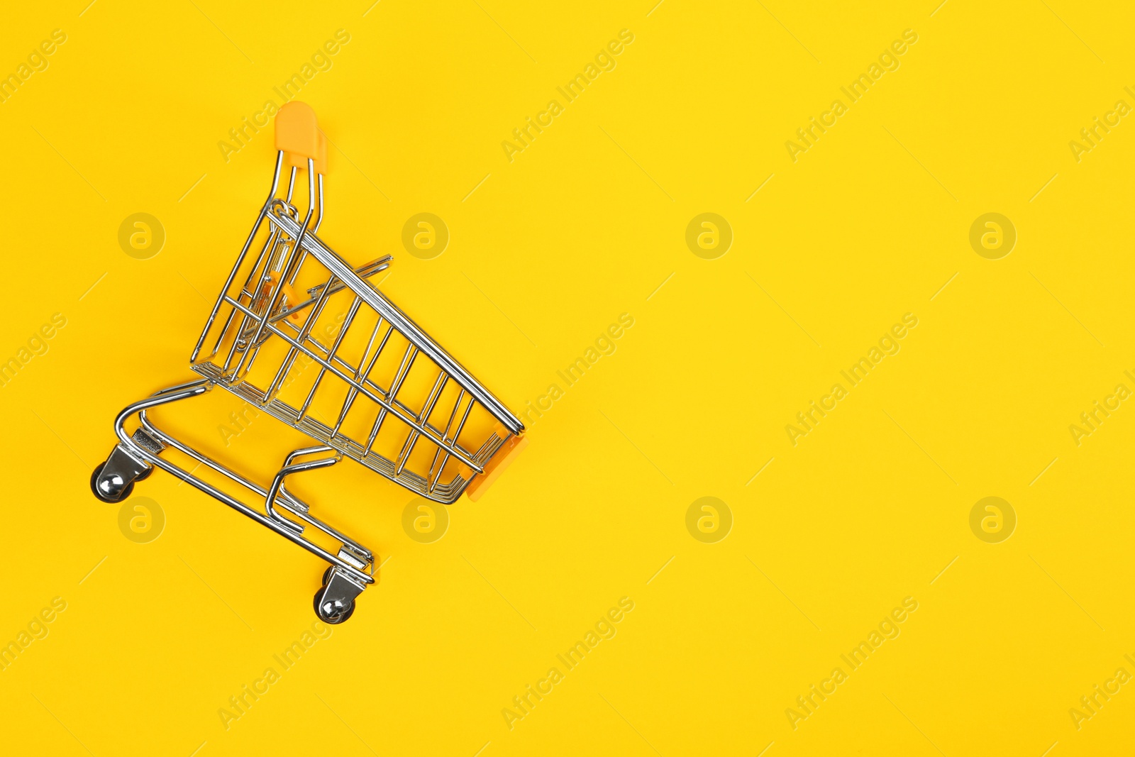 Photo of Empty shopping trolley on color background, top view. Space for text