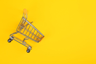 Empty shopping trolley on color background, top view. Space for text