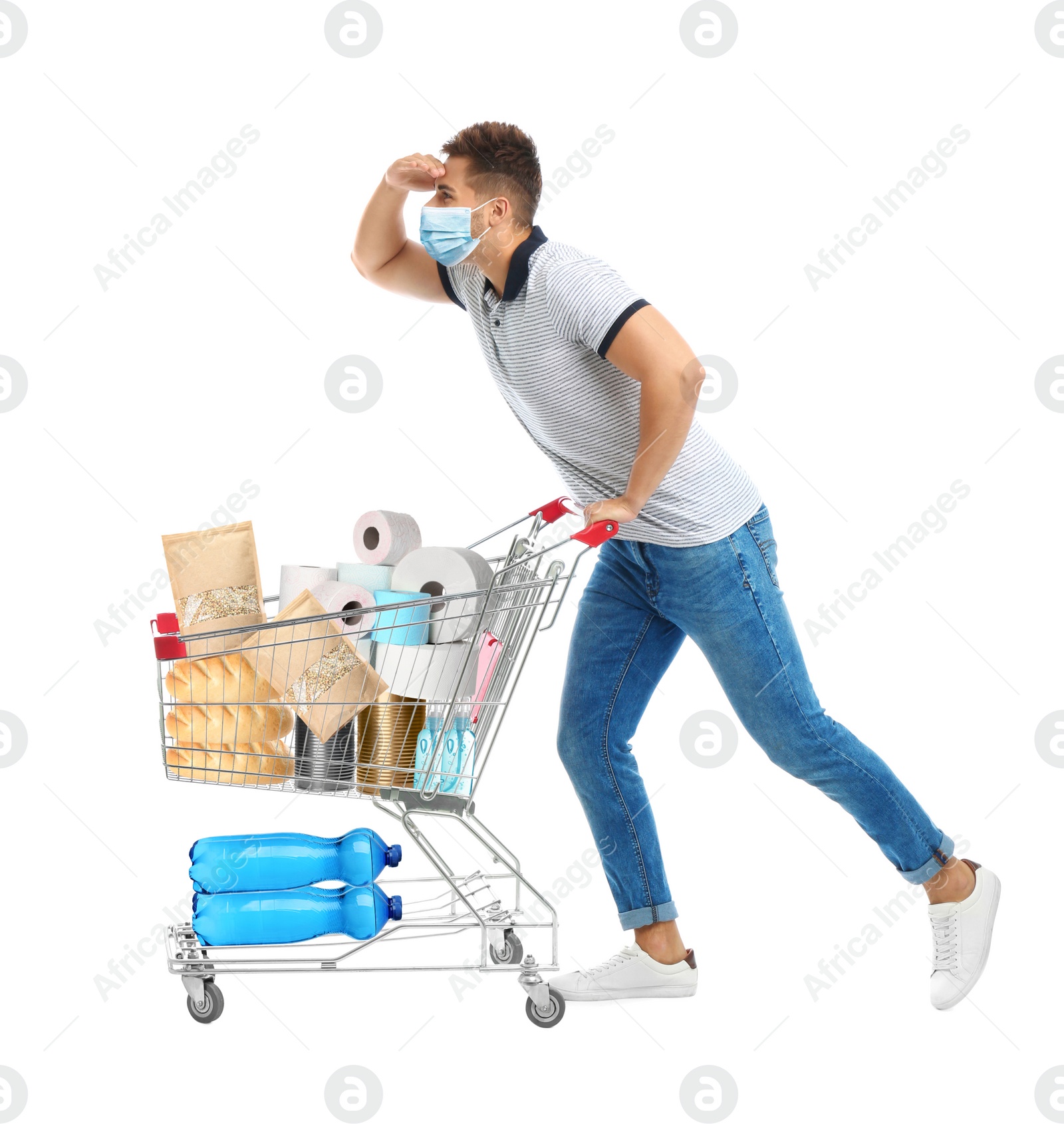 Image of Young man in medical mask and shopping cart with purchases on white background. Coronavirus pandemic 