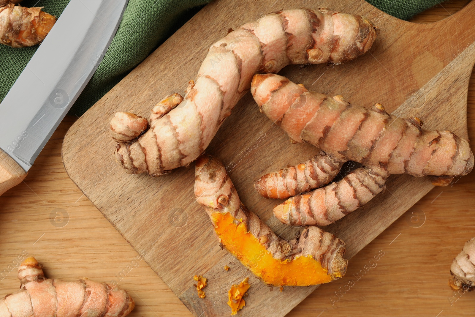 Photo of Many raw turmeric roots on wooden table, flat lay