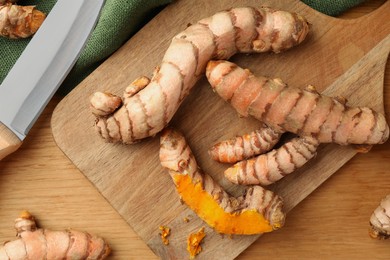 Many raw turmeric roots on wooden table, flat lay